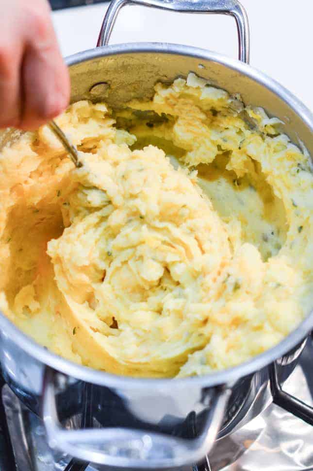 Mixing cheese, garlic, parsley and salt into potatoes