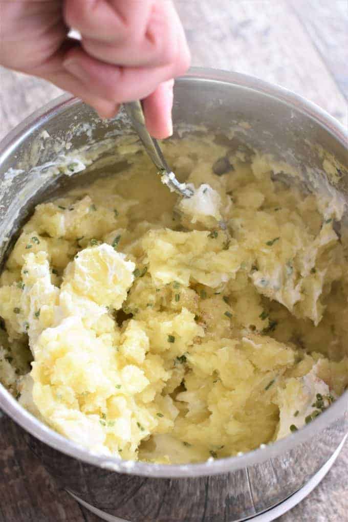 Stirring seasonings and sour cream into mashed potatoes