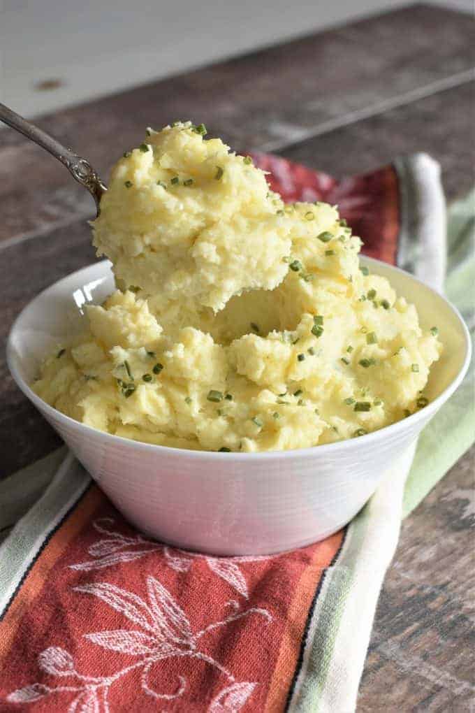 Scooping mashed potatoes with a spoon from a bowl