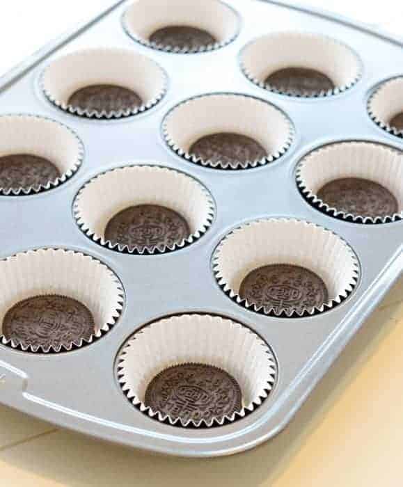 baking cups with an Oreo cookie in each one in a muffin pan