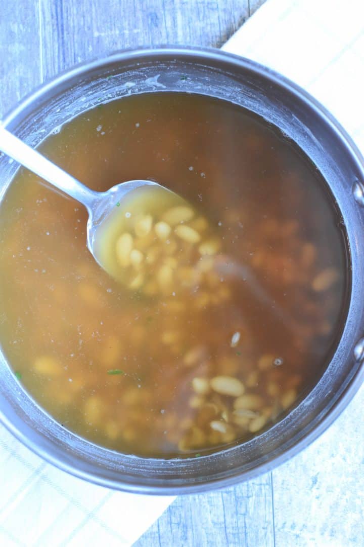 Stirring broth into the bean mixture in the soup pot