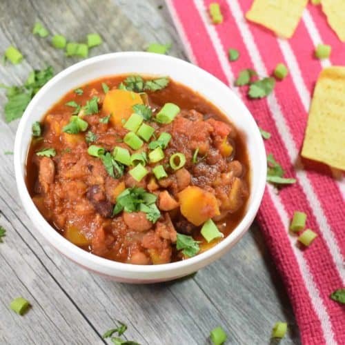 chili in a bowl topped with scallions and cilantro