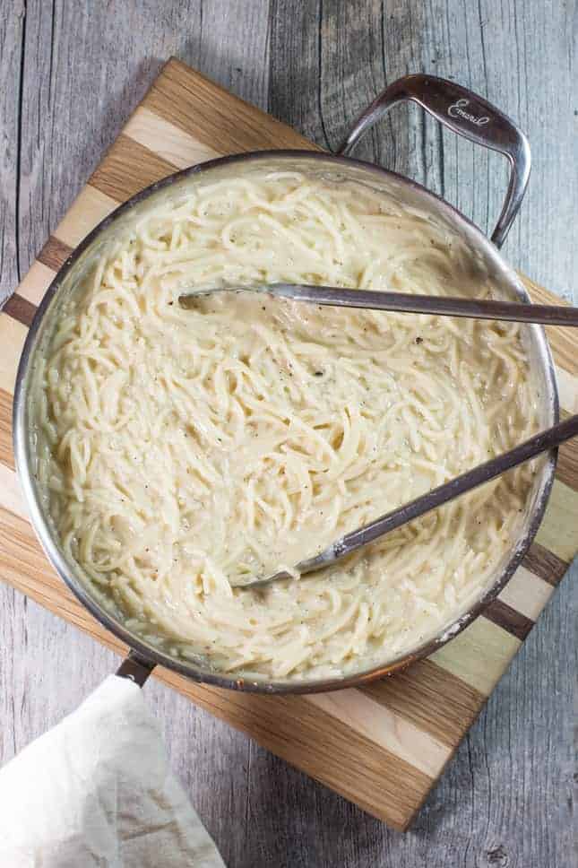 overhead of finished cacio e pepe in sauté pan with tongs in it