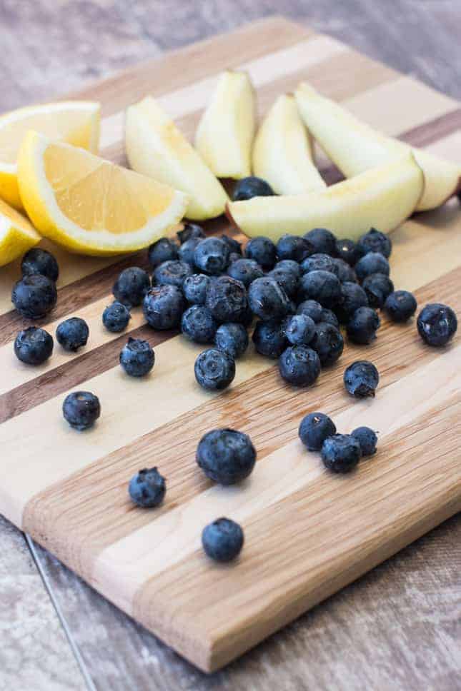 apples, blueberries and lemons on a wooden board