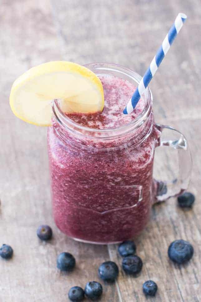 front view of apple blueberry smoothie in mason jar garnished with a lemon slice with straw 