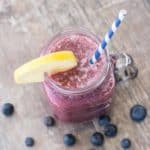 overhead of smoothie in mason jar with lemon wedge and a straw in it