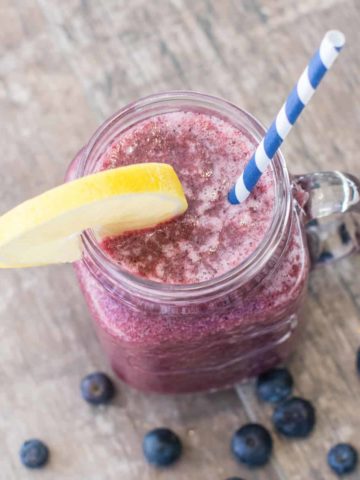 overhead of smoothie in mason jar with lemon wedge and a straw in it