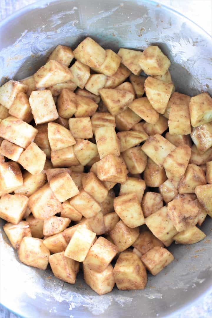 Apples mixed with seasonings in a mixing bowl