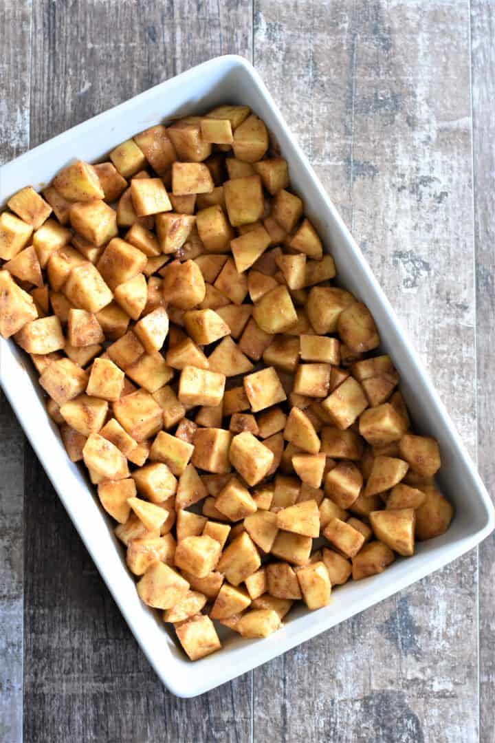 seasoned apples in a white baking dish