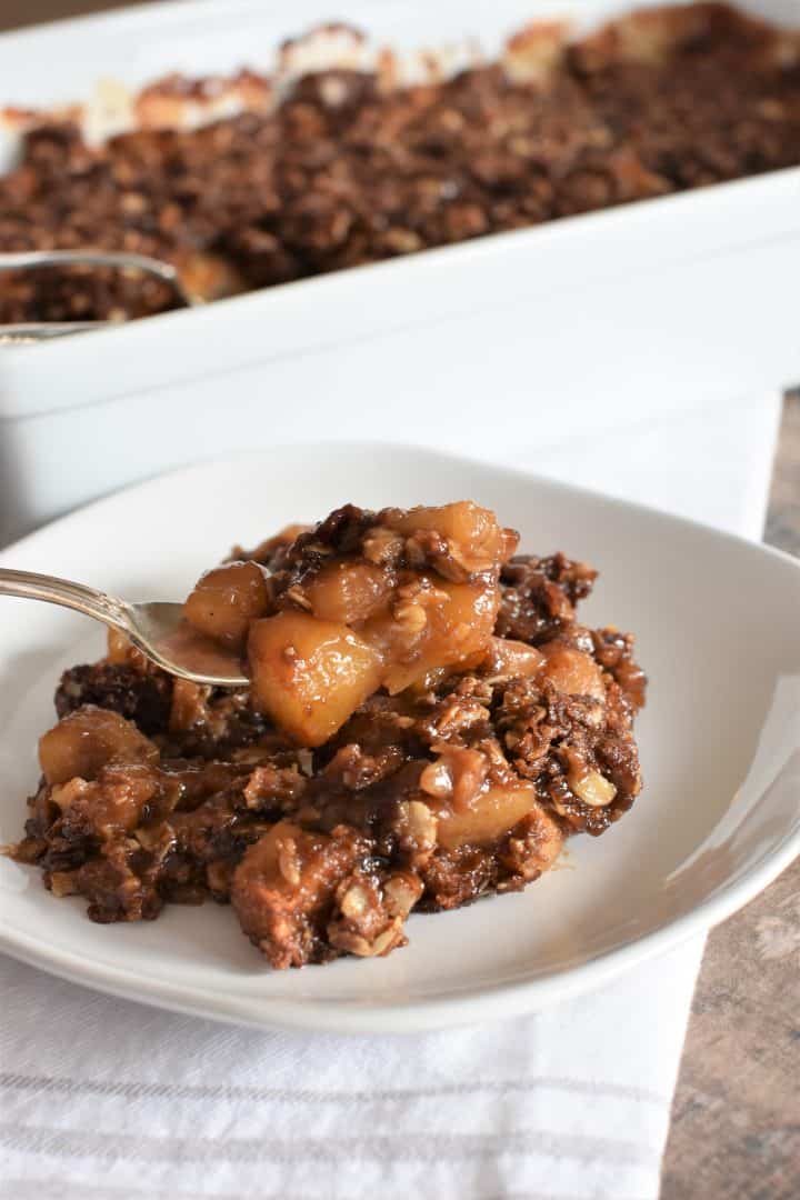 serving of vegan apple crisp on a white plate with a fork going into it