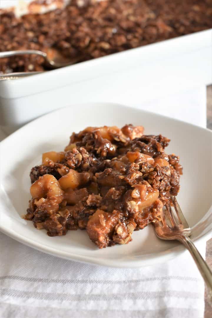 serving of apple crisp on a white plate with a fork