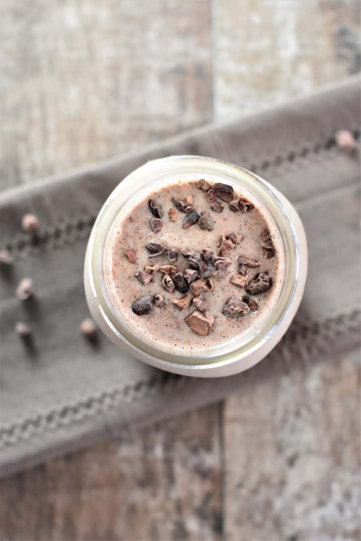 overhead of Banana Almond Butter Cacao Smoothie in a Mason Jar with cacao nibs on top