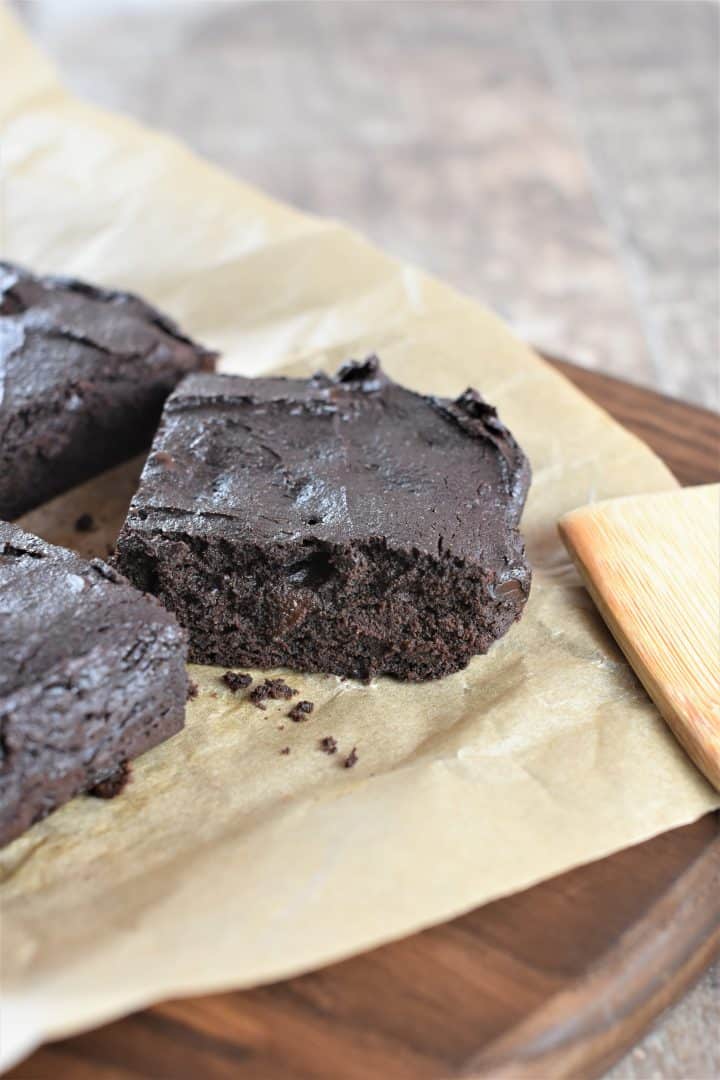 close-up of cut brownie on parchment with parts of other brownies in view
