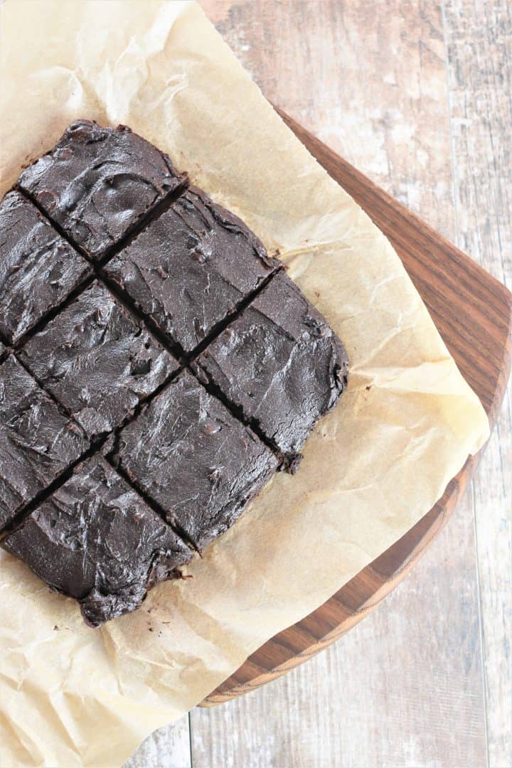 overhead of cut brownies on parchment on wooden board