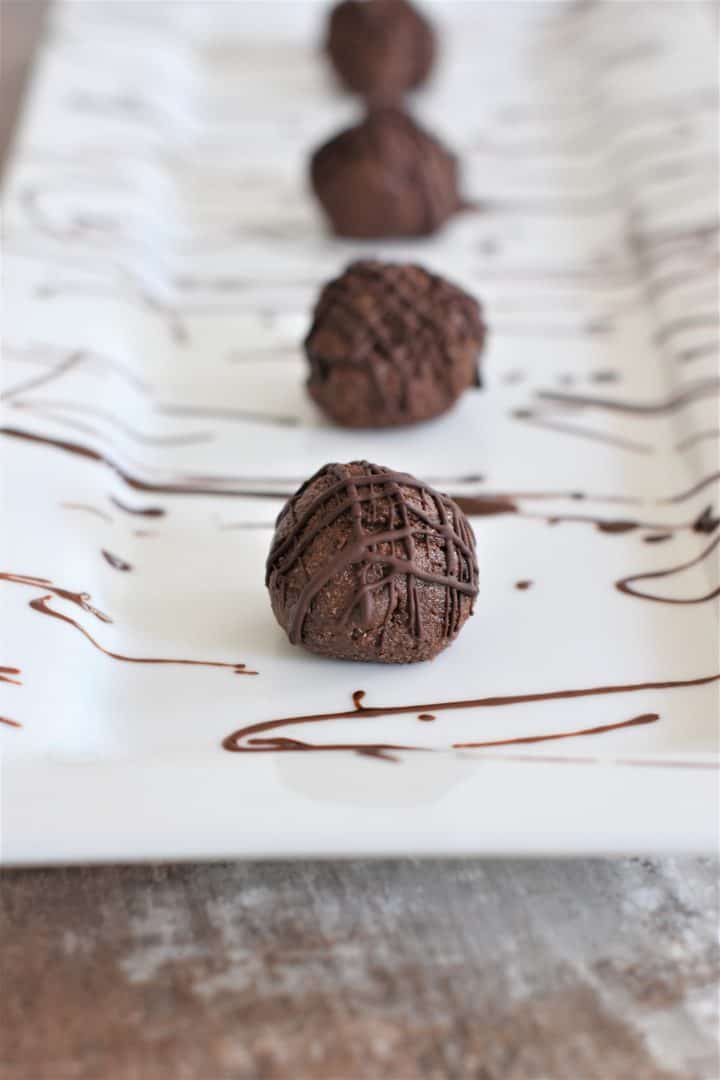 front view of cookie bites on white serving platter with chocolate drizzle all around