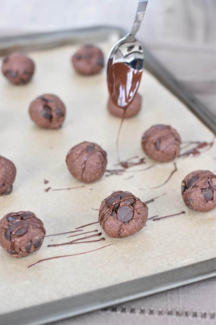 Drizzling chocolate on the cookie bites with a spoon