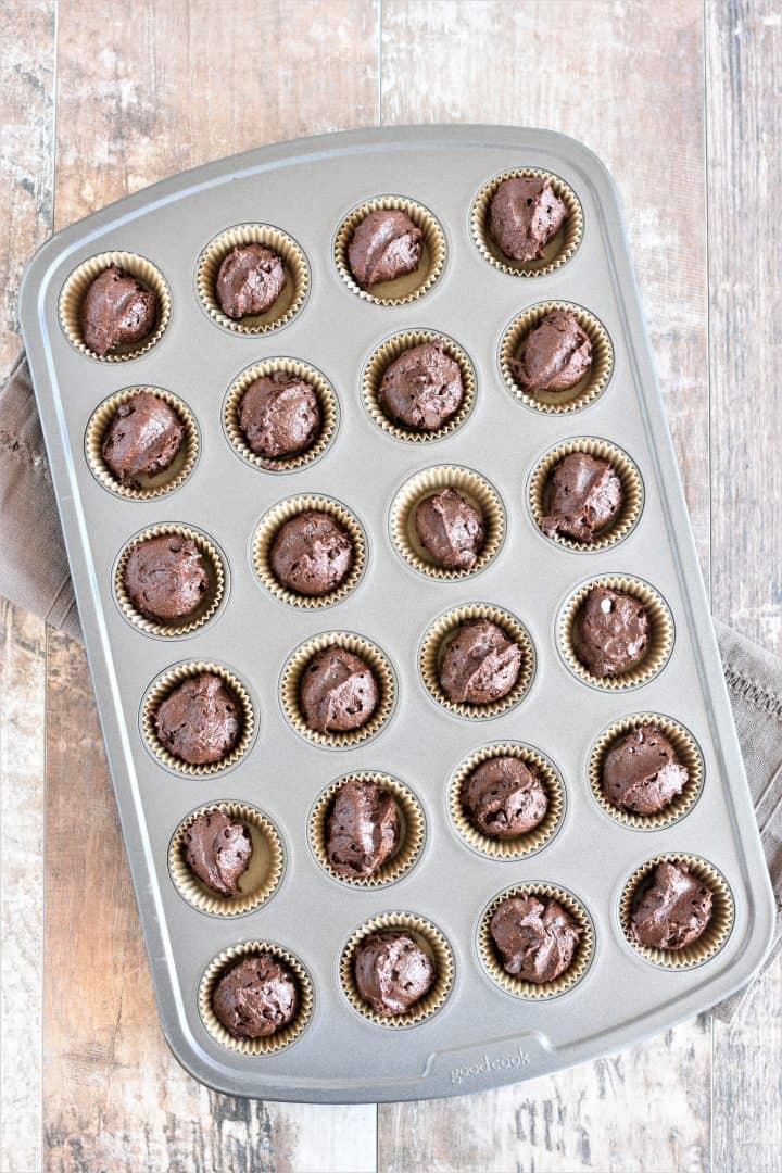 mini muffin tin filled with brownie batter in mini muffin cups in each cavity