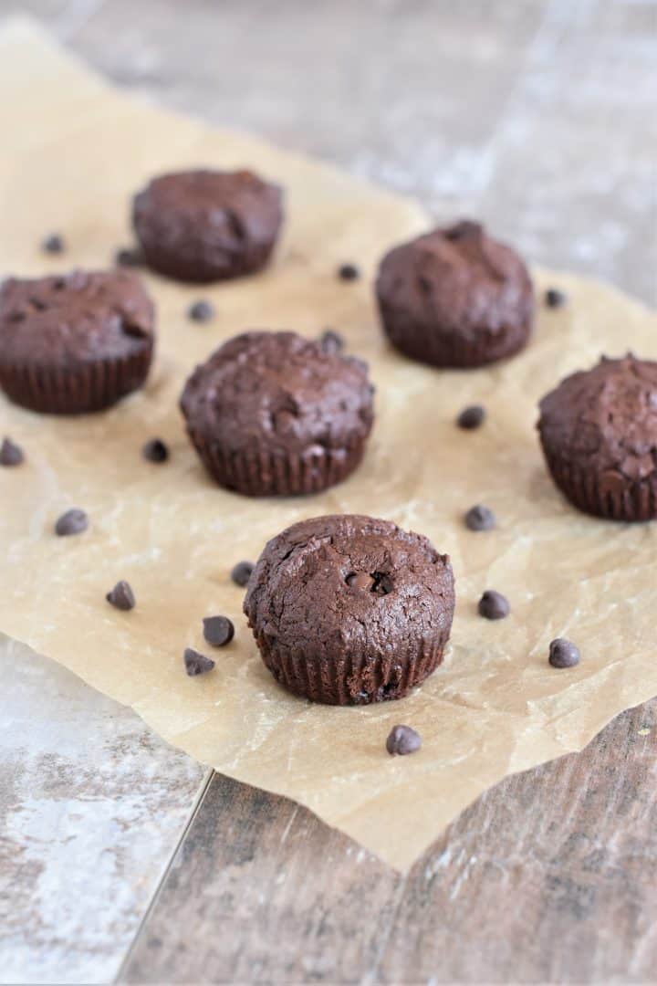 some mini brownies on parchment with chocolate chips around
