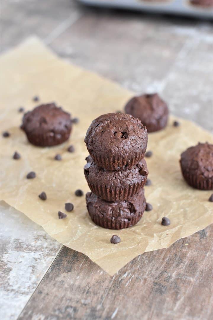 three mini brownies stacked up on parchment with some more around