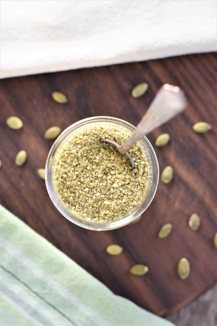 overhead of pumpkin seed cheese in mason jar with spoon in it