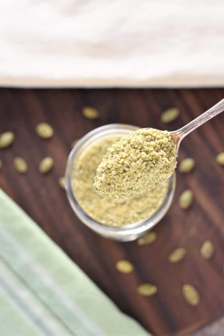 holding spoonful of pumpkin seed cheese over mason jar of the rest