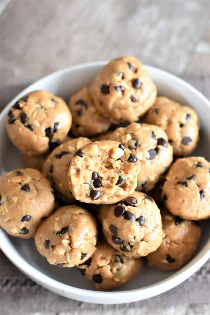 overhead of peanut butter balls in white bowl with bite taken out of the one on top