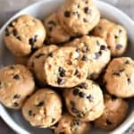 Energy balls in a white bowl with a bite taken out of the top one