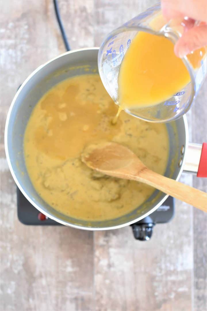 Vegetable broth being poured into saucepan