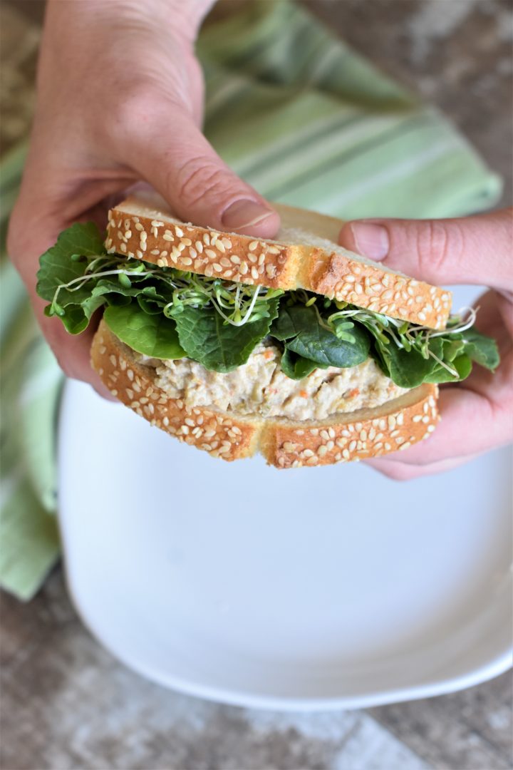 Holding a sandwich with two hands over a plate