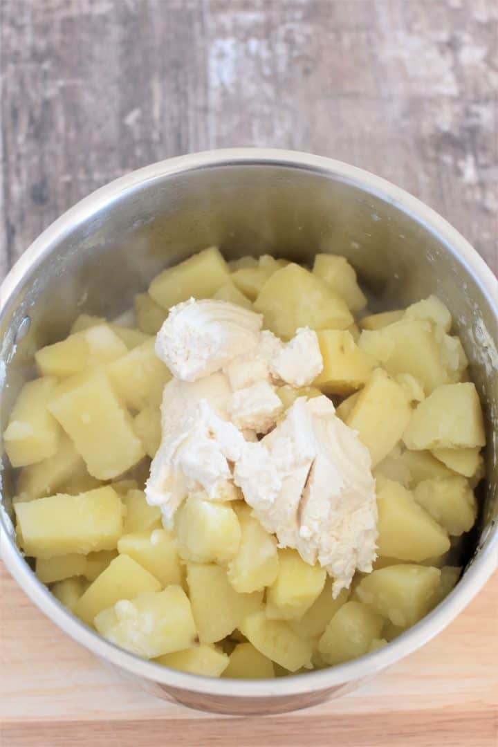 potatoes in pot with cream cheese, milk, salt and pepper added