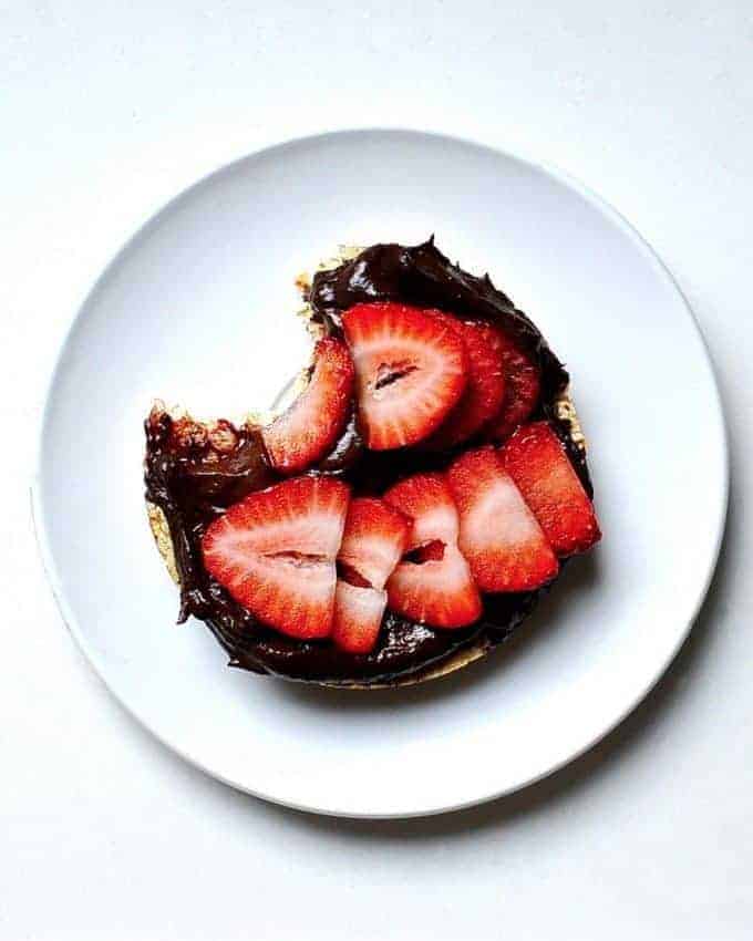 Vegan nutella on a bagel with strawberries on top