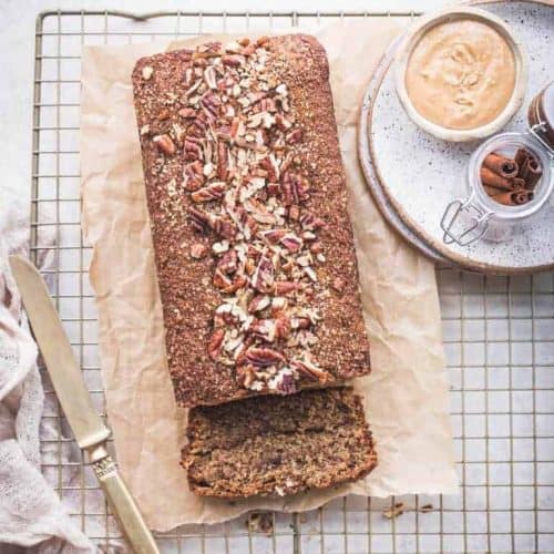 loaf of banana bread on parchment with first piece cut off and lying down