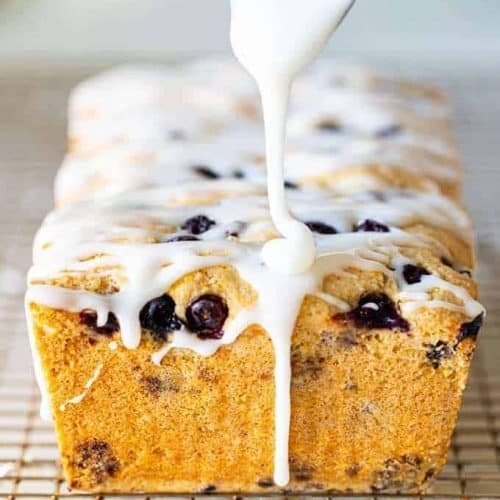 spoon dripping icing onto loaf of lemon cake