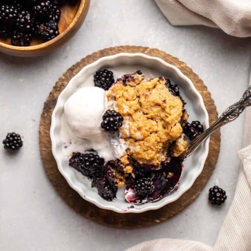 overhead of blackberry cobbler with spoon in it and some ice cream