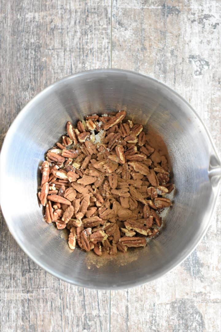 Cinnamon, maple syrup and salt added to the raw pecans in a mixing bowl