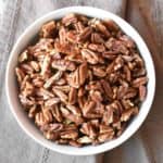 overhead of roasted pecans in a white bowl