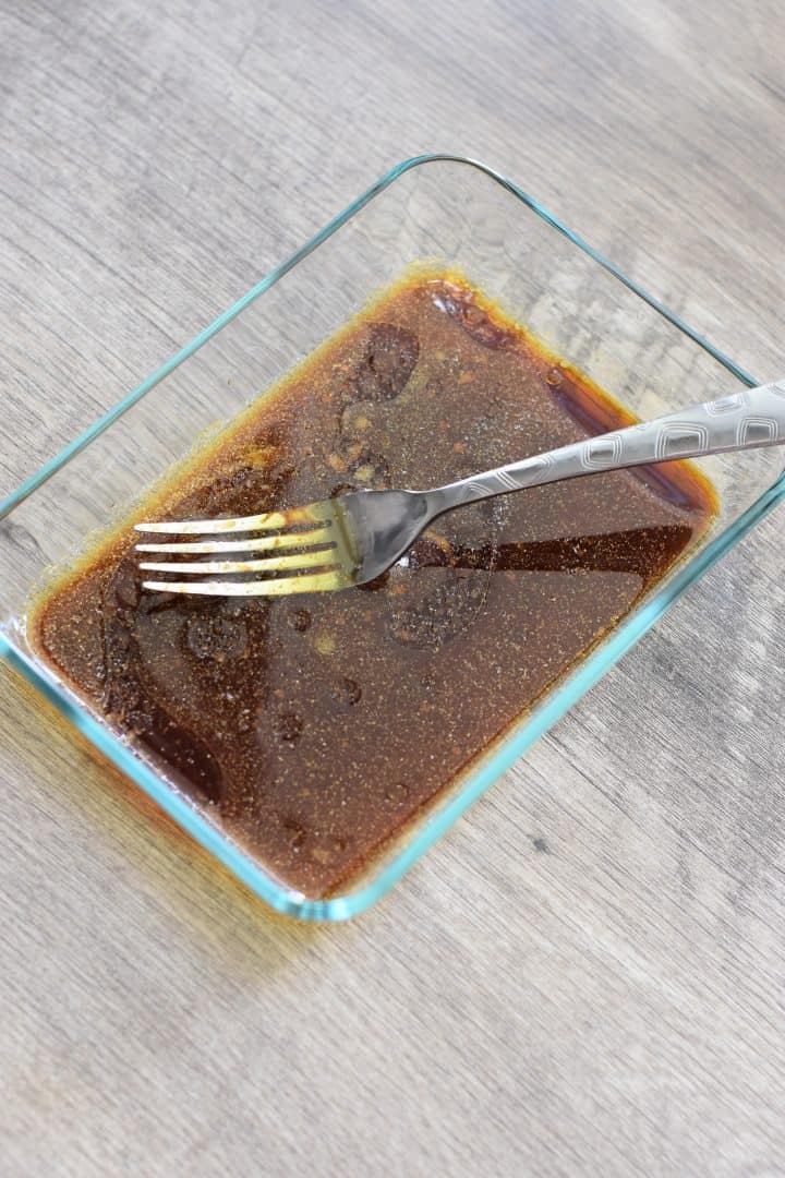 Tempeh marinade ingredients whisked together in glass dish with a fork