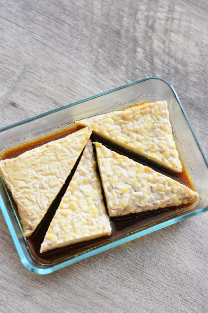 tempeh triangles added to marinade in glass dish