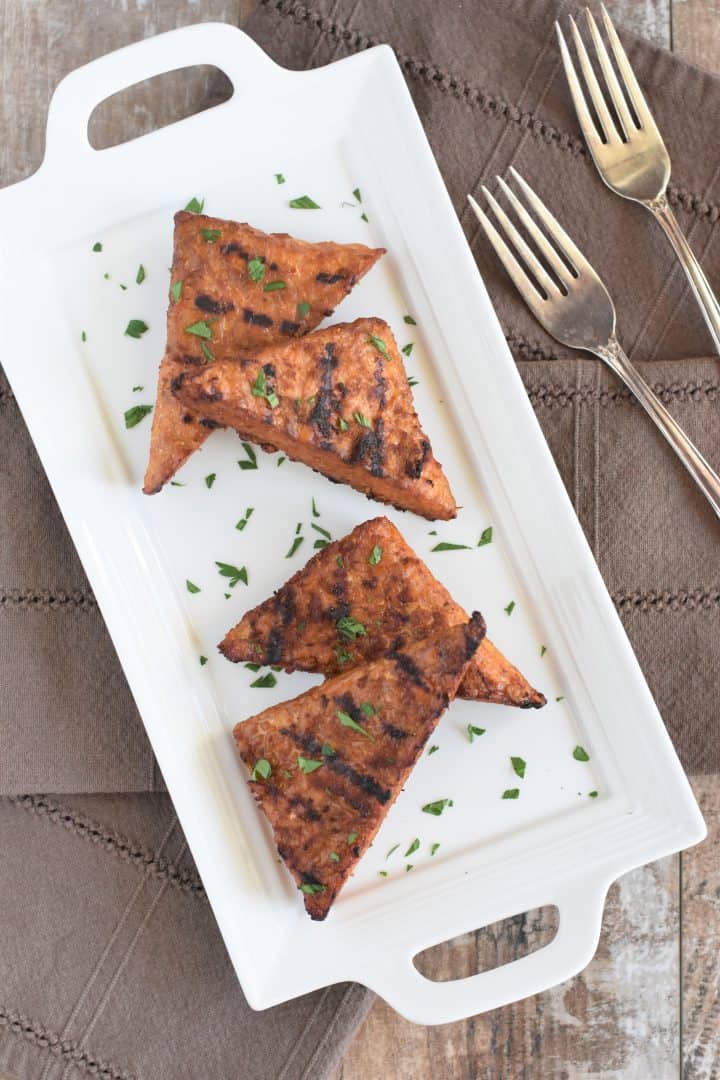 grilled tempeh garnished with parsley on a white platter