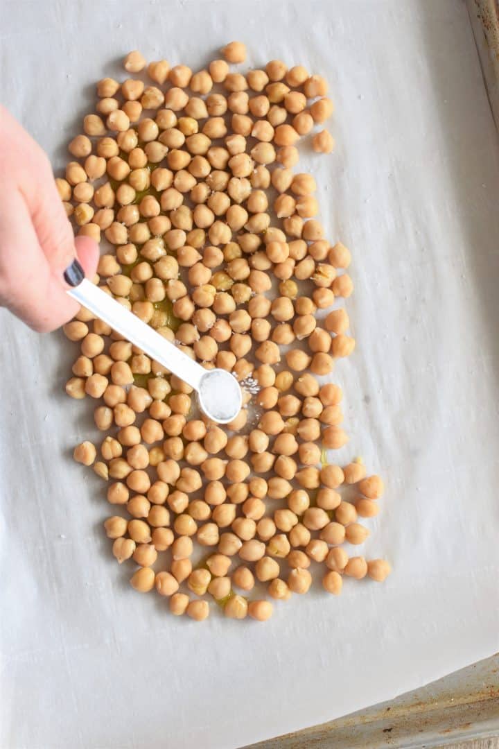 Sprinkling on salt after adding the oil to the chickpeas on the baking sheet