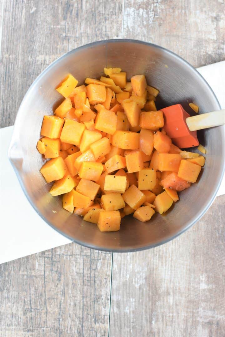 Stirring the butternut squash to evenly coat with olive oil, salt and pepper