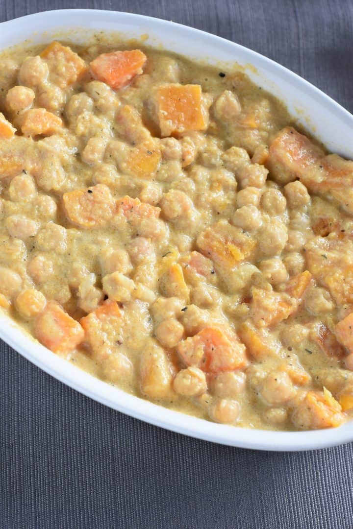 Sauce mixed into chickpeas and butternut squash in casserole dish