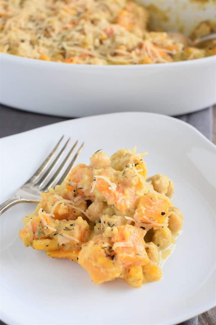 A Scoop of the casserole on a plate with a fork and the casserole dish in the background