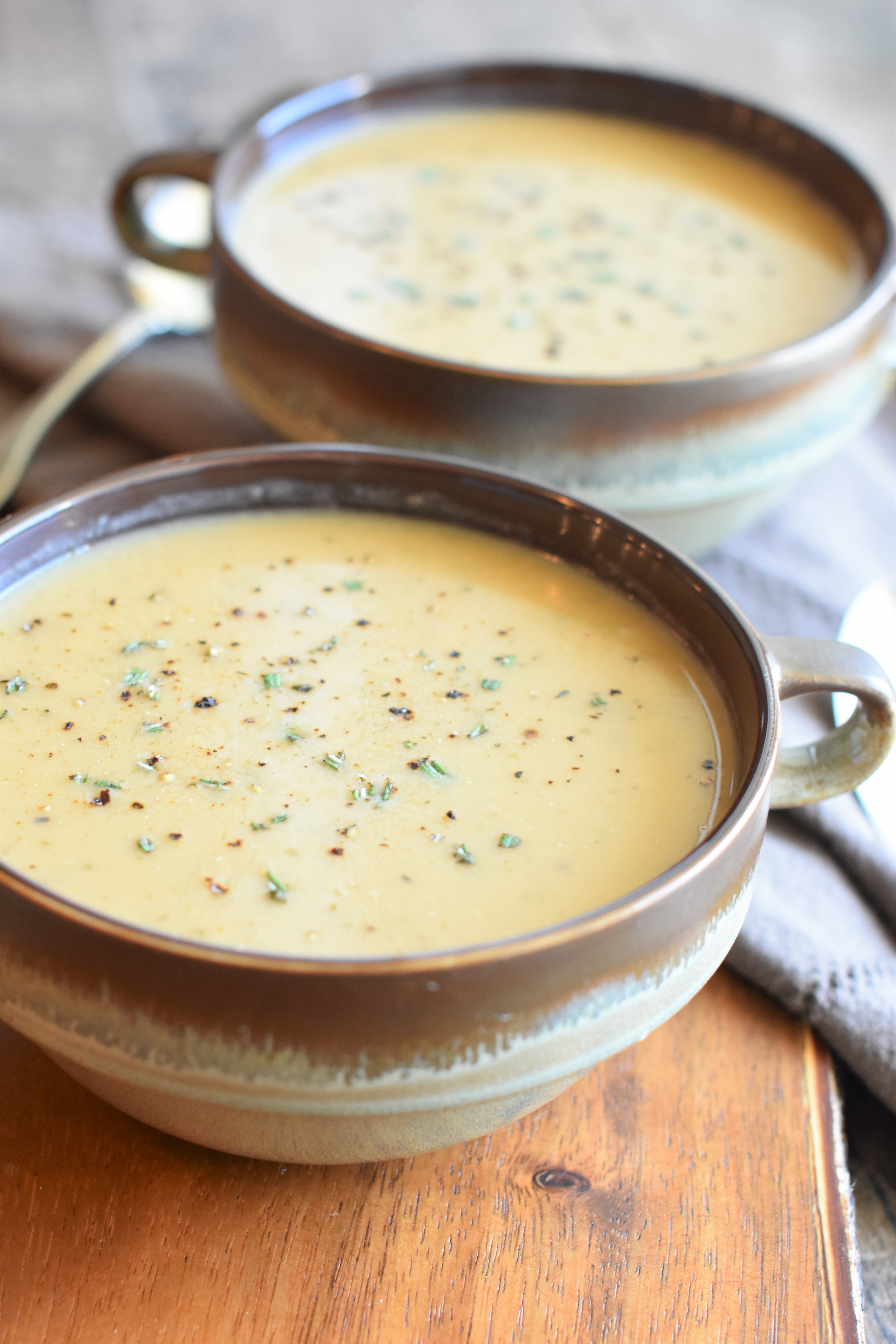 front view of soup in two rustic bowls with spoons next to them