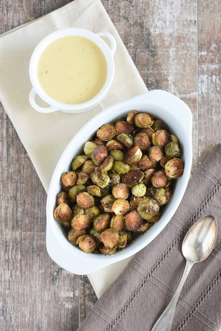 overhead of balsamic roasted Brussels sprouts in a white dish with bechamel sauce to the left and a spoon to the right