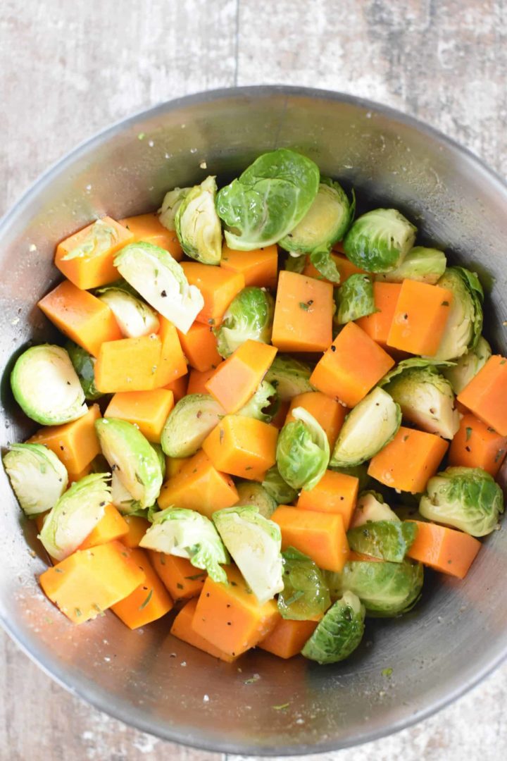 Olive oil, maple syrup, lemon juice and seasonings stirred into butternut squash and Brussels sprouts in mixing bowl