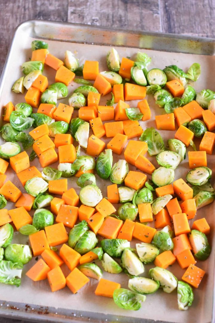 Butternut squash and Brussels sprouts spread out on baking sheet