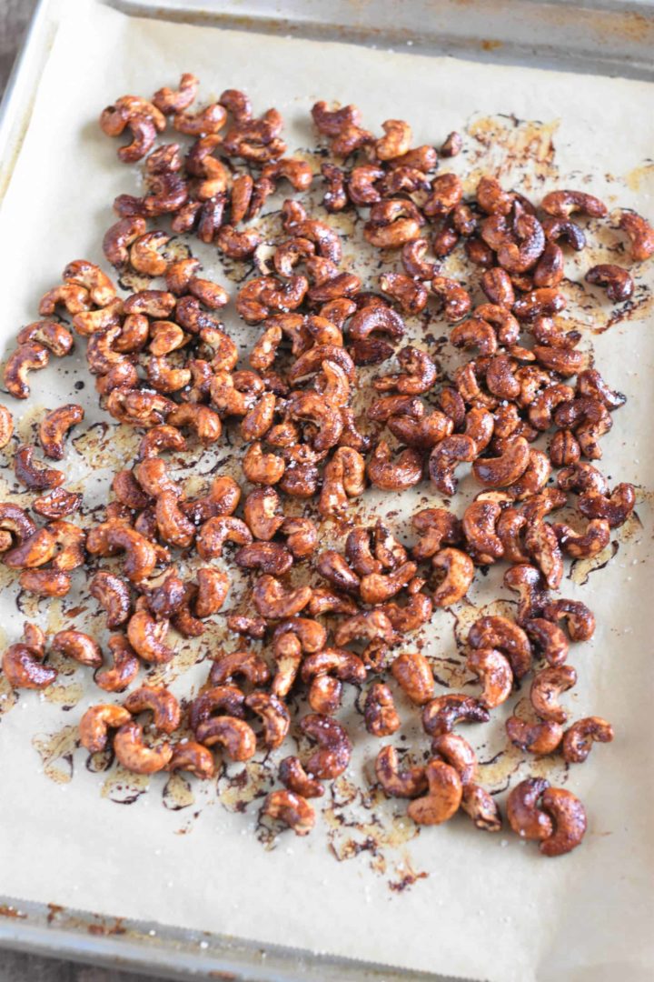 Roasted cashews on baking sheet with sea salt sprinkled on top