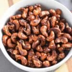 overhead of cashews in a white bowl on a wooden board