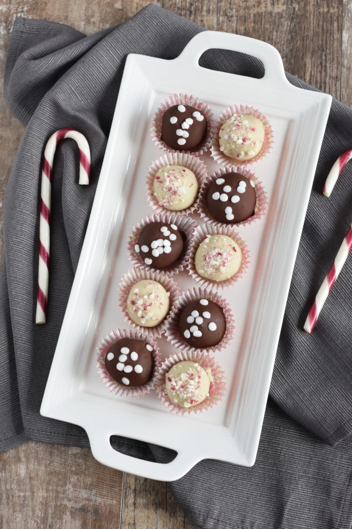 overhead of truffles on white serving platter on kitchen towel with candy canes next to it